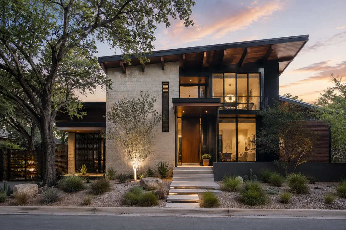 Contemporary two-story urban infill residence with limestone, dark metal, large windows, mature trees, and native landscaping in Austin