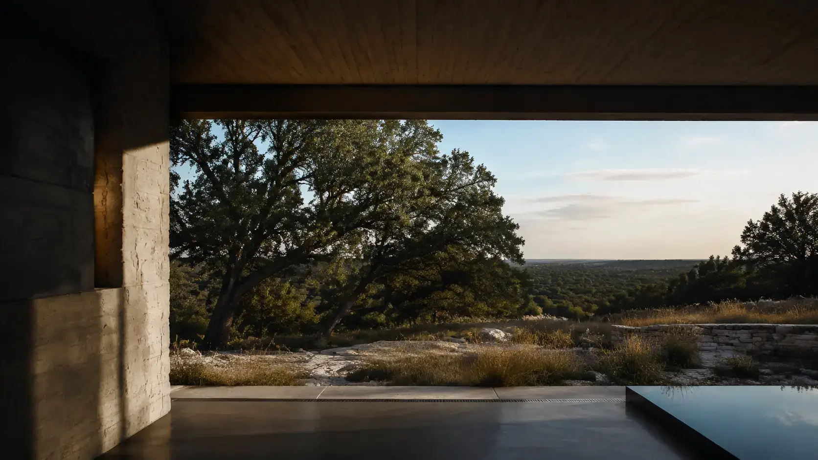 View from a contemporary Texas home framing native Hill Country oaks and limestone terrain