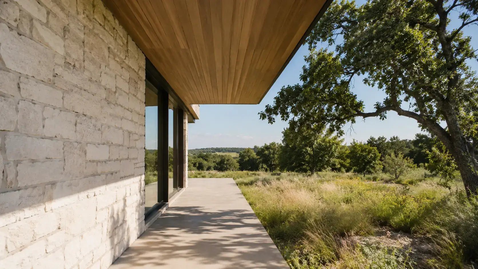 Deep roof overhang shading limestone walls and glazing on a Texas Hill Country residence