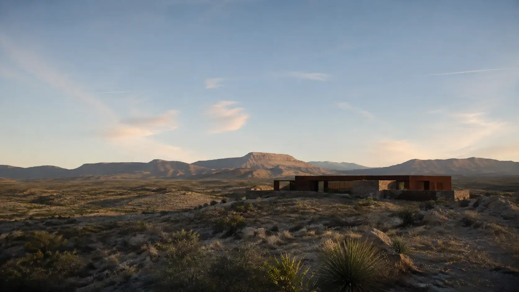 Low contemporary residence integrated with desert vegetation and distant mountains in West Texas